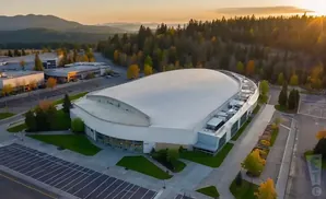 Aerial view of a large domed stadium surrounded by trees and buildings at sunset.