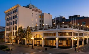 A historic downtown building at dusk, lit by streetlights and decorative lights on trees.