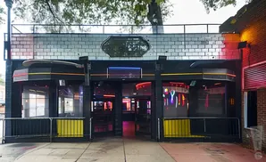 Exterior of a nightclub with black facade, neon lights, and patterned windows.