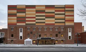 Building with brick lower floors and colorful horizontal panels on the upper facade.