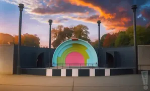 Outdoor amphitheater with a colorful, arched backdrop and dramatic sunset sky.