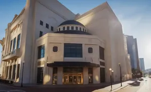Exterior of a modern building with a dome, large windows, and an entrance with golden doors.
