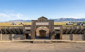 Wooden rodeo entrance with bleachers and mountains in the background.
