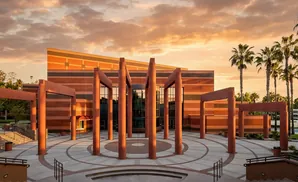 A sunset illuminates a modern building with red brick and a circular plaza with tall pillars.