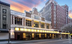 Exterior of a historic theater with a marquee and ornate architectural details at sunset.