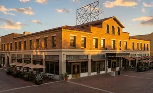 Golden hour light on a tan brick building with arched windows and a courtyard patio.