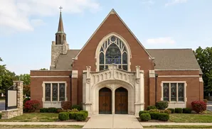 A brick church with a steeple and stained glass windows.