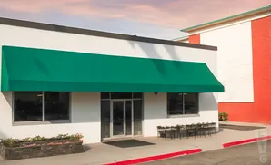A white building with a green awning over the entrance and windows.