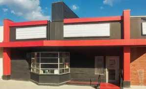 Red and black building with marquee lights and a glass ticket booth.