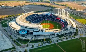 Aerial view of a baseball stadium with surrounding fields and a highway.