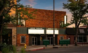 Aggie Theatre marquee glows in the sunset light, with trees and a yellow fire hydrant in front.