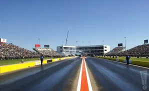 Drag strip with packed stands and a clear blue sky.