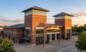 Brick building with two towers and large glass windows, at sunset.