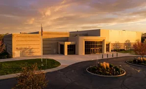 Modern tan building with large windows at sunset.