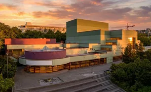 Modern building with a circular entrance under a sunset sky.