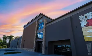 Modern building with stone and brick accents under a colorful sunset sky.