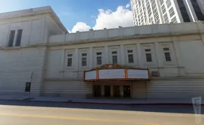 A classic theater with a marquee and ornate details, partially obscured by a modern skyscraper.