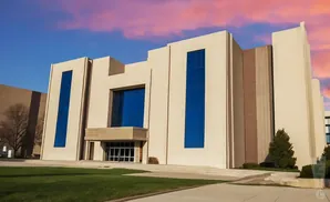 Modern beige building with large blue windows against a pink and blue sunset sky.