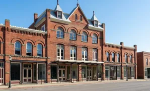 A historic brick building with arched windows and storefronts under a clear blue sky.