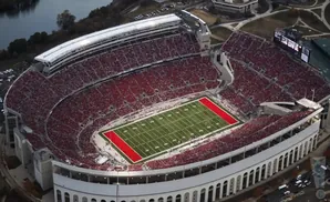 Aerial view of a packed football stadium with red seats and a green field with red end zones.