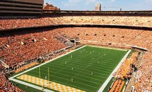 Aerial view of a crowded football stadium filled with orange-clad fans during a game.