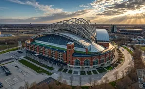 Aerial view of American Family Field stadium with a retractable roof and brick facade at sunset.