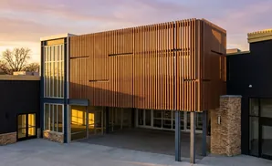 Modern building with wood-slatted facade and large windows at sunset.