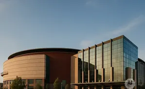 Modern arena and office building with glass facade under a clear blue sky.