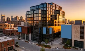 Modern glass buildings in a city skyline at sunset.