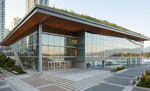 Modern convention center with a green roof, glass facade, and waterfront view.