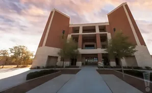 Wide-angle view of a modern brick building with stone accents and balconies, under a dramatic sky.