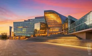 Modern glass building with warm lighting at sunset.