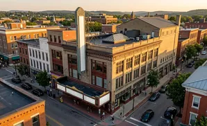 Aerial view of a historic theater and surrounding brick buildings bathed in golden hour light.