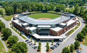 Aerial view of a baseball stadium with brick buildings and a green field.