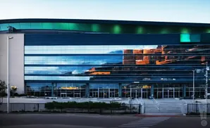Modern building with reflective glass windows showing sky and building reflections.