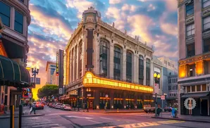Golden hour sunset over a city street with a historic theater and glowing marquee.