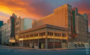 A historic theater with a neon marquee at sunset.