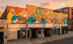 A theater facade features a large, colorful mural of abstract shapes and figures.