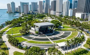 Open-air amphitheater and stage with a city skyline and water in the background.