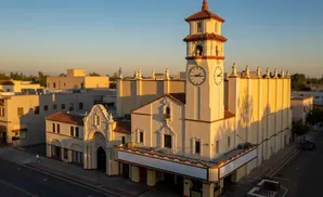 Spanish Colonial Revival theater with a clock tower at sunset.