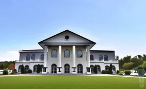 A grand white building with a triangular roof and columns, fronted by a lush green lawn.