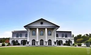 Grand white building with columns and arched windows, set against a clear blue sky with a manicured lawn in the foreground.