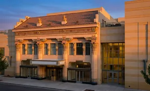 Art Deco building with ornate columns, tiled roof, and modern glass entryway.