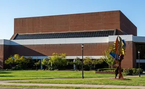 Sculpture in front of a large brick building with a band of windows.