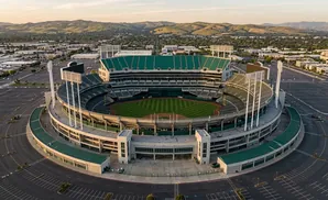 Aerial view of a baseball stadium surrounded by empty parking lots and a distant city.