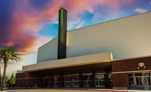 A large building with a prominent green and black tower against a dramatic sunset sky.