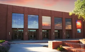 Red brick building with large windows reflecting a sunset sky.