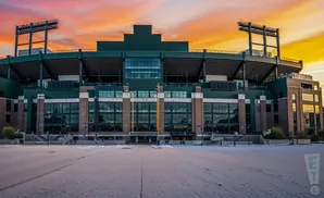 A baseball stadium at sunset, with a colorful sky and snow on the ground.