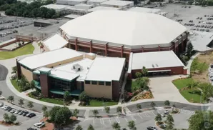Aerial view of a large white domed arena with surrounding buildings and parking lots.