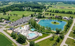Aerial view of a water park with pools, slides, and a large lake surrounded by trees and parking lots.